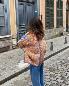 Quilted floral jacket detail with vintage patterns shown in a European street setting
