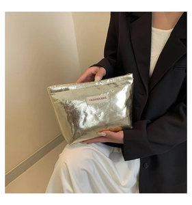 Detail of metallic gold cosmetic bag with pleated texture and white fashion label
