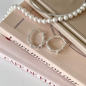 Minimalist 925 sterling silver twisted hoop earrings on books with pearl necklace