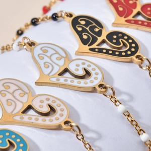 Detail of bohemian gold chain bracelets with heart enamel charms and colorful beads