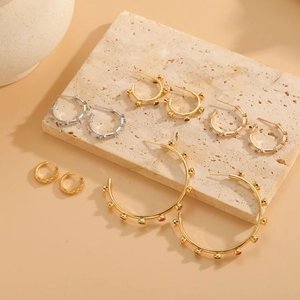 Close-up of assorted gold and silver geometric hoop earrings with colorful zircon stones