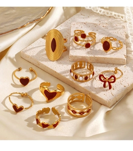 Close-up of vintage gold rings set with red enamel hearts and bows on stone textures