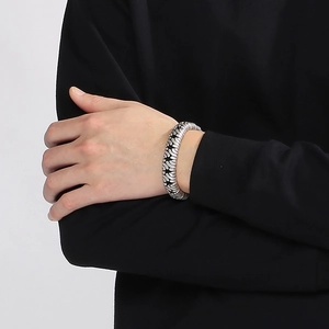 Detail view of a vintage silver stainless steel cuff bracelet on a male model's wrist