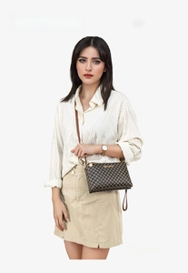 Detailed close-up of dark brown polka dot pattern and sleek shoulder strap on a crossbody bag