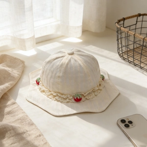 Détail du chapeau de soleil bébé avec bordure en dentelle crème et décors fraises