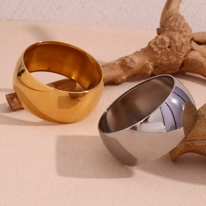 Close-up of minimalist gold and silver wide bangles with a high-polished mirror finish