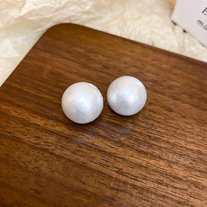 Macro di orecchini a perno con perle bianche su legno scuro e sfondo di carta stropicciata