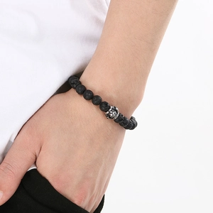 Detailed close-up of volcanic lava stone beads and antique silver skull charm on wrist