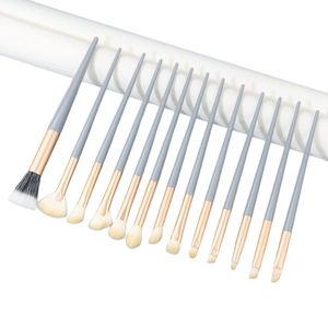 Professional 12-piece soft makeup brush set with gray handles and gold ferrules on white stand