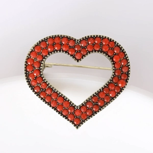 Close-up of vintage heart brooch with red gems and antique bronze metal finish