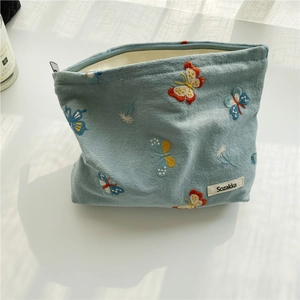 Detail of embroidered butterflies on blue canvas makeup bag with zipper closure