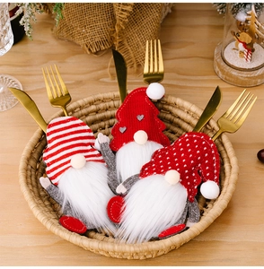 Close-up of three gnome-themed Christmas cutlery holders with knitted texture and faux fur