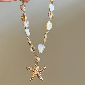 Close-up of beach style shell beaded necklace with a golden starfish charm detail