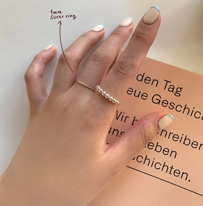 Close-up of 1mm silver beaded ring on model hand with elegant natural lighting