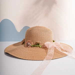 Detail of wide brim straw hat with handmade flowers and pink silk ribbon for summer beach