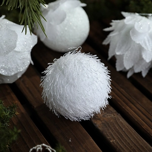 White fuzzy foam Christmas balls with leaf petals and sequins on pine branches