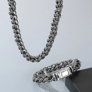 Macro detail of silver braided chain necklace and bracelet set with rectangular clasp