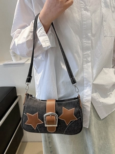 Close-up of retro denim underarm bag with brown leather star patches and buckle detail