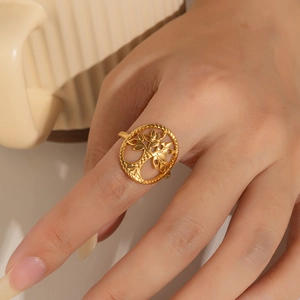 Close-up of golden hollow Tree of Life ring on finger showing delicate metal craft