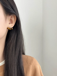 Close-up of triple tiger eye stone stud earrings on model with silver needles