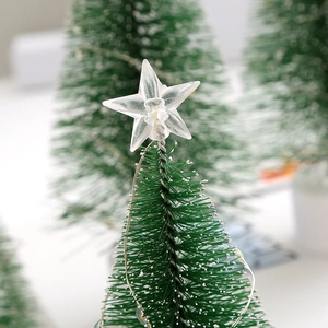 Close-up of a mini Christmas tree with a transparent star topper and snow-flocked branches