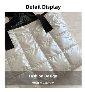 Detailed close-up of white quilted puffer tote with black strap and sateen finish