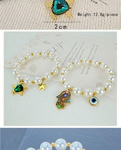 Detail of beaded pearl bracelets with turtle and evil eye charms in gold finish
