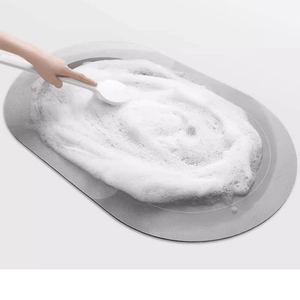 Absorbent cartoon bathroom mat in gray oval shape being cleaned with soapy white foam