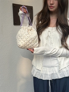 Detail of quilted drawstring storage bag with purple floral pattern and leather label