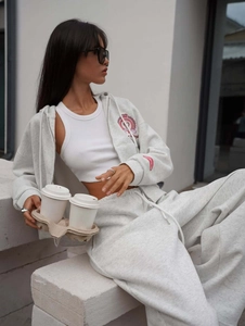 Close-up of light grey cotton knit texture and vintage red crest embroidery on hoodie