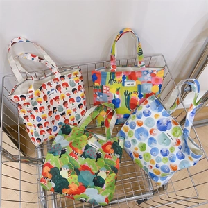 Detail of four floral canvas tote bags in a metal basket with a woven brand label