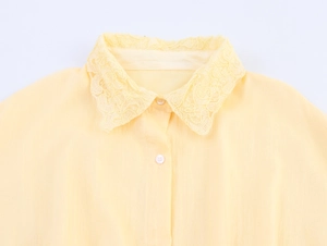 Détail d'une robe chemise jaune clair avec col en dentelle délicate et petits boutons