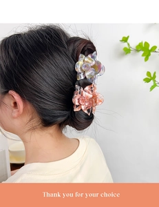Detail showing two floral claw clips in blue and pink worn by a model on white background