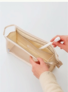 Detailed view of hand placing toothbrush into a mesh travel organizer bag
