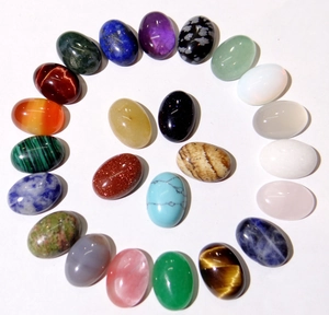 Spiral arrangement of 21 colorful oval gemstone cabochons on white background