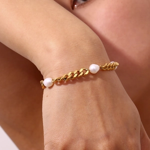 Close-up of golden stainless steel Cuban chain bracelet with three white pearls on wrist
