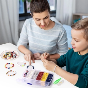 Close-up of mother and child crafting DIY colorful alphabet bead bracelets at home
