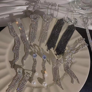 Elegant bow fringe earrings with sparkling crystals and pearls on a white tray