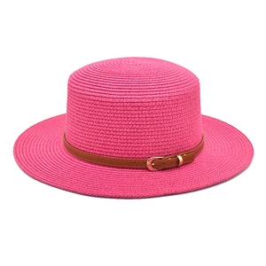 Detail view of woven rose pink straw sun hat with brown faux leather belt and gold buckle