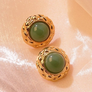 Macro shot of vintage gold quilted earrings with green cabochon resin on pink silk