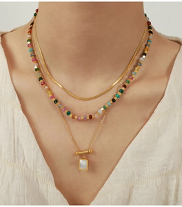 Detail of triple-layered 18K gold plated necklace with colorful beads and shell pendant