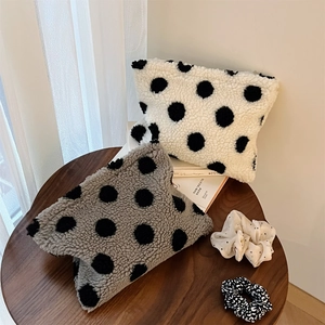 Detailed texture of plush lamb wool makeup bags with large black polka dots