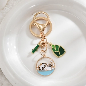 Detail of golden panda keychain with bamboo and shoot charms on white ceramic plate