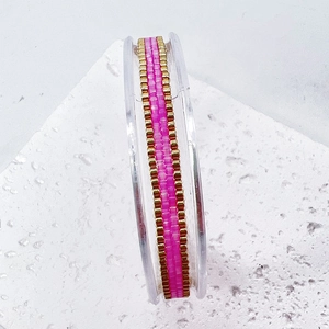 Detail view of pink and gold handmade woven beaded bracelet on an acrylic display