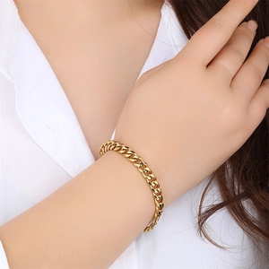 Minimalist gold Cuban link bracelet for men and women on model's wrist with shiny metal finish