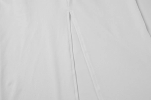 Gros plan sur le tissu blanc d'une robe montrant la fente de l'ourlet et la texture fluide