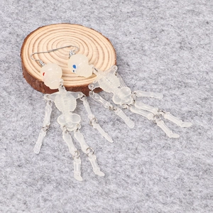 Detailed close-up of articulated skeleton earrings with silver hooks on wood background