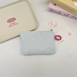 Macro detail of quilted light blue coin purse with cloud pattern and pink zipper loop