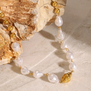 Elegant gold-plated stainless steel necklace with white baroque pearls on a natural stone