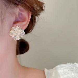 Close-up of floral earring featuring pearlescent petals and small crystal accents